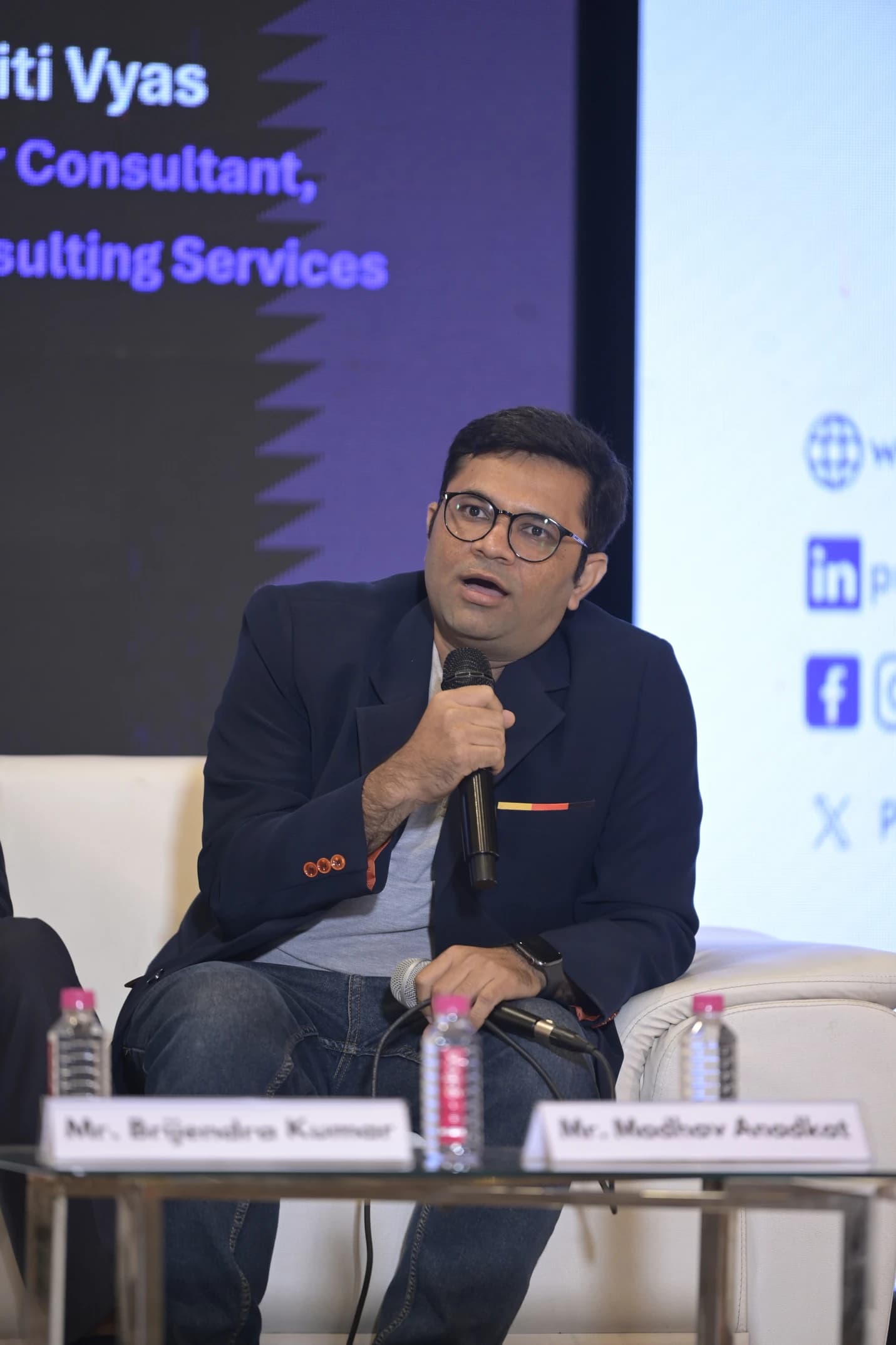 Madhav Anadkat seated with a microphone during a panel discussion, mid-answer