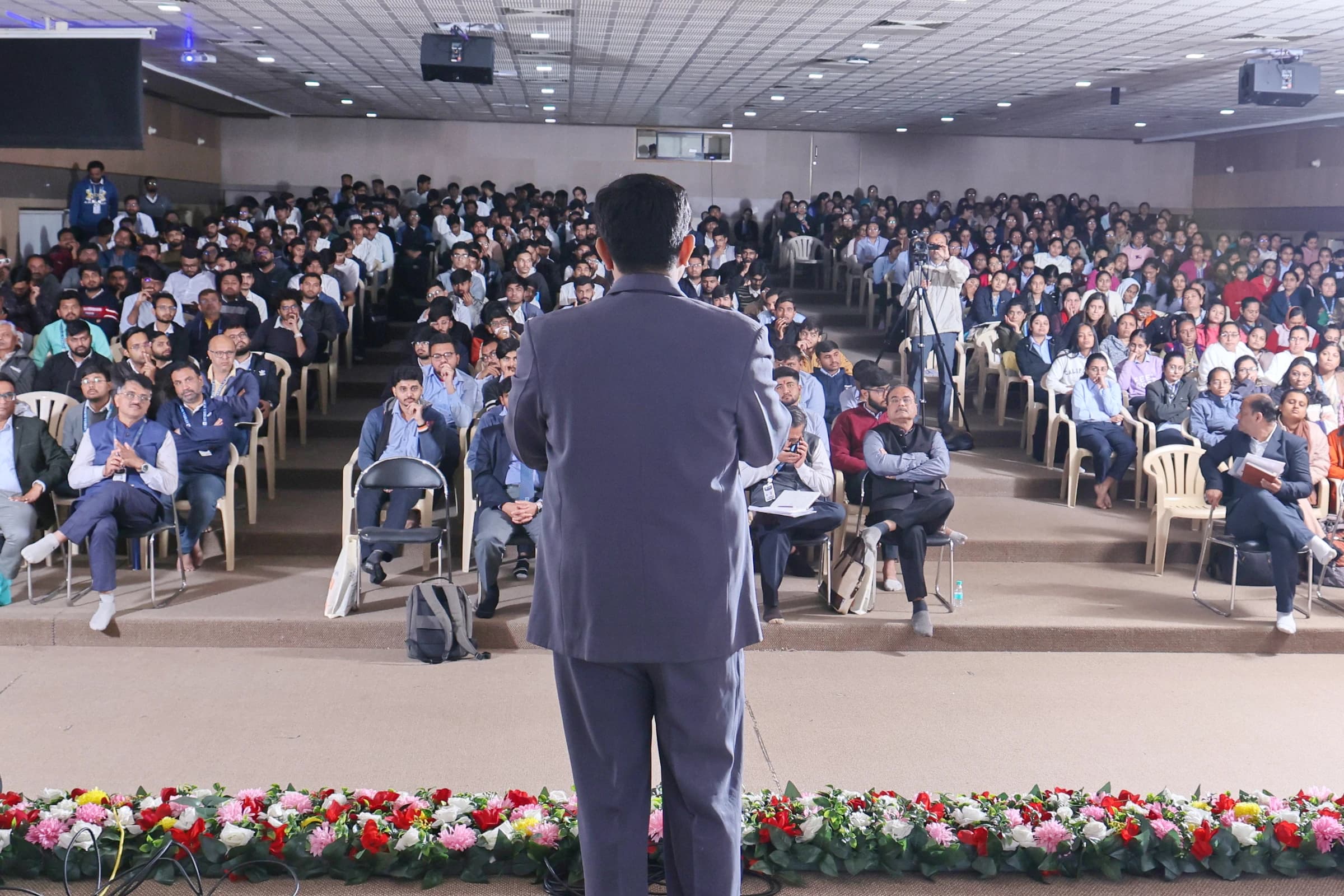 Speaking to a packed audience — over-the-shoulder shot of Madhav at the lectern, room full