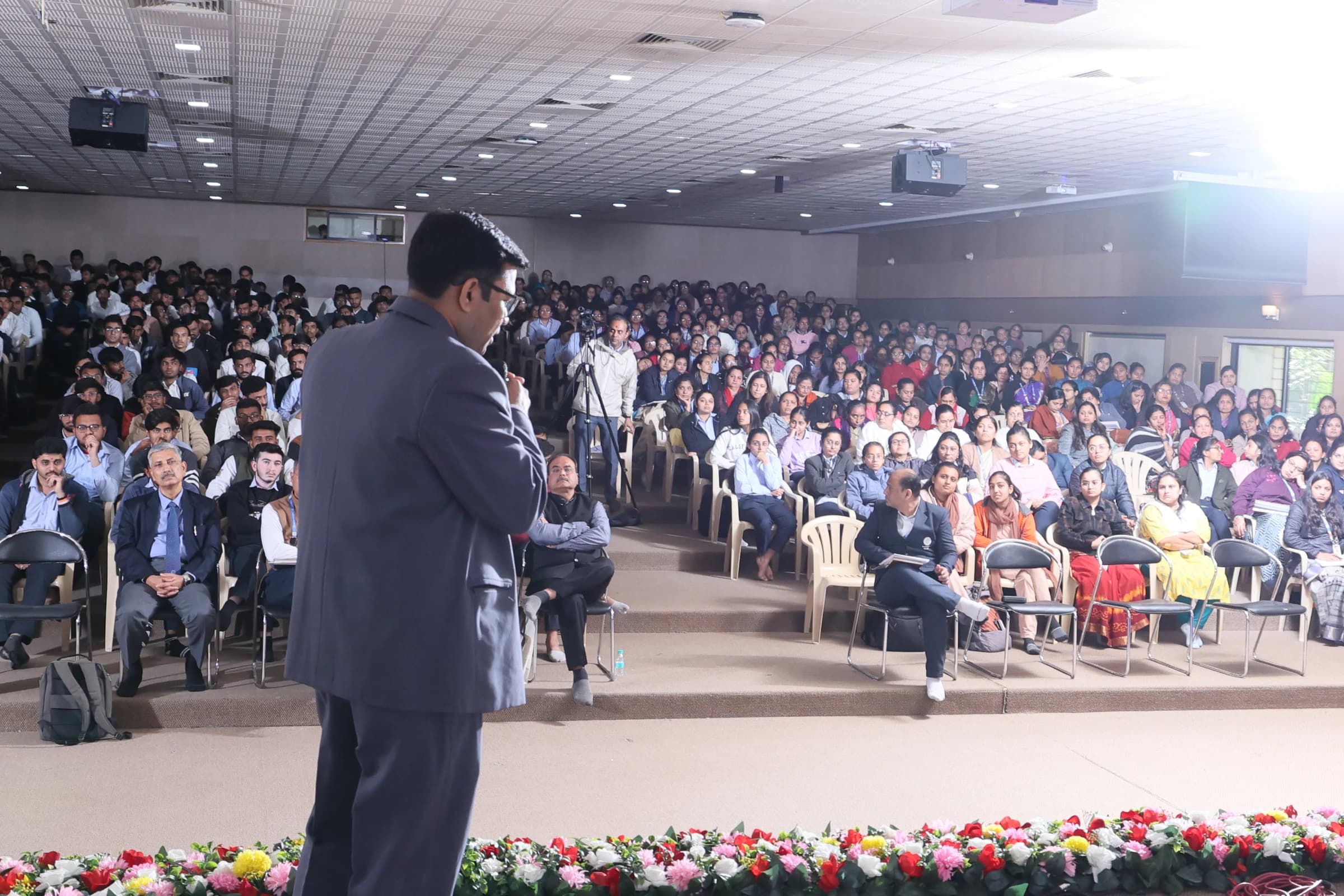 Madhav Anadkat addressing a full conference room — three-quarter angle